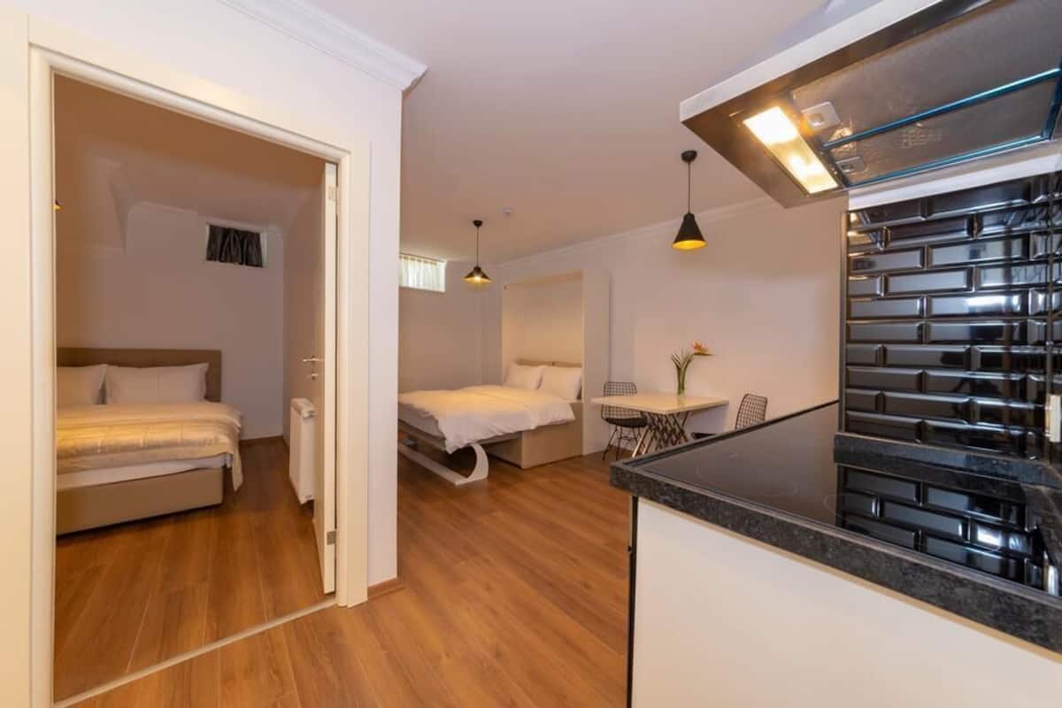 A compact living space with a kitchenette, a dining area, and a bedroom with a bed and a small table.