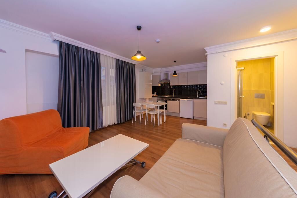 A compact living space with a sofa, a dining table, and a kitchenette.