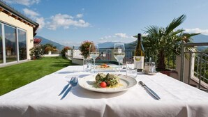 A table set for a meal with a mountain view, a bottle of wine, and a glass of water. - Hotel Haus an der Luck (Barbiano)