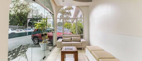 A waiting area with a sofa, a coffee table, and a view through a glass door.