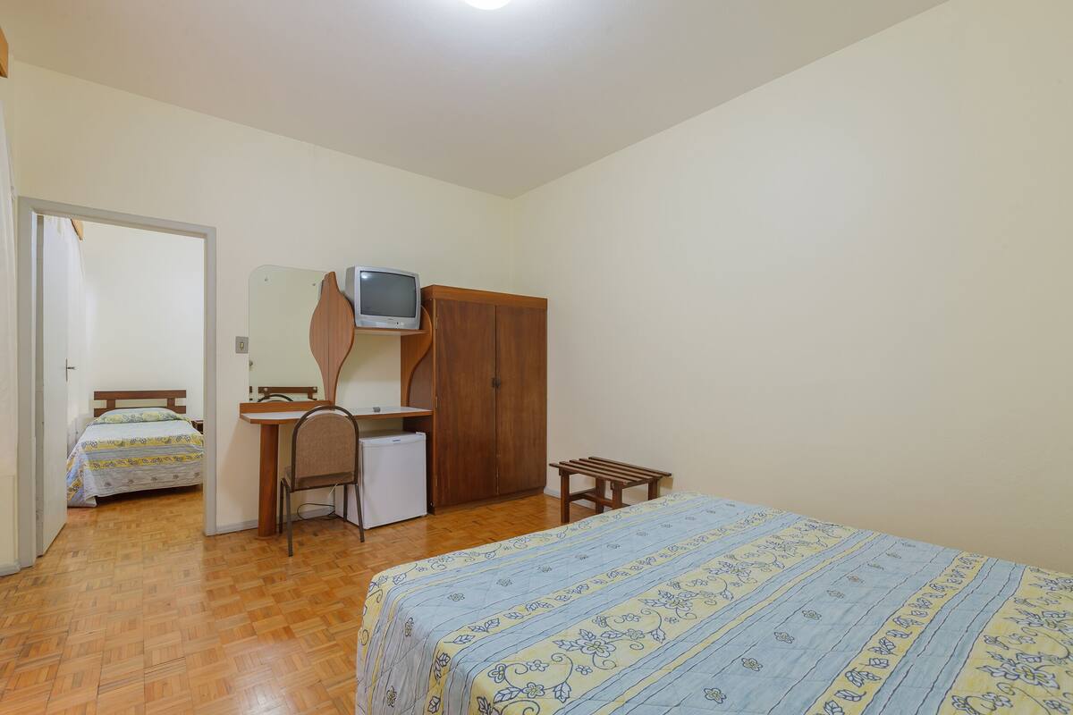 A bedroom with a bed, a desk, a chair, a television, and a wardrobe.