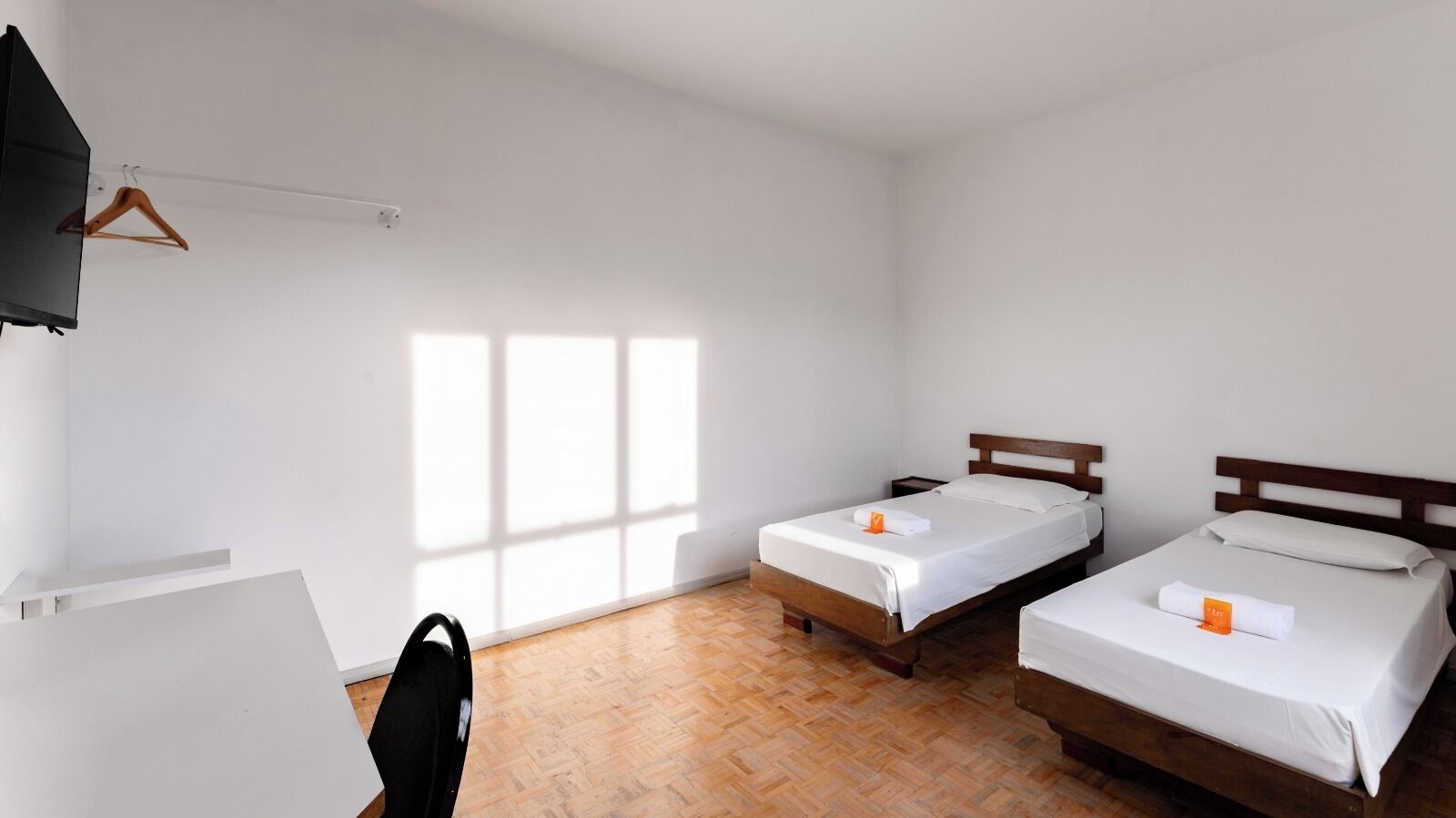 A room with two beds, a desk, and a TV.