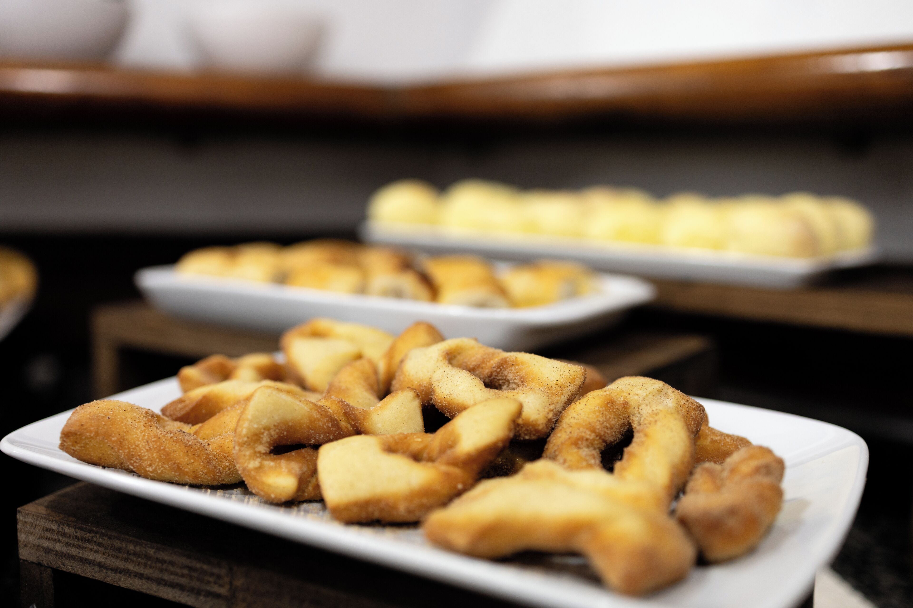Una mesa de buffet con diversos alimentos, incluyendo una bandeja con productos empanizados y fritos al frente.