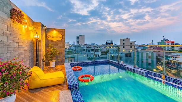 Una piscina en la azotea con baldosas azules, un sofá amarillo y un letrero que dice "Casa Brojo House".