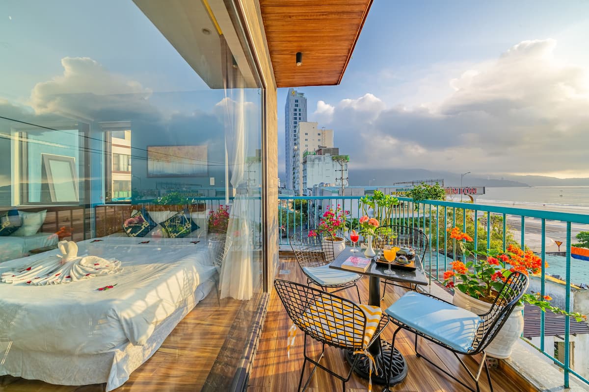 A balcony with a bed, seating area, and potted plants.