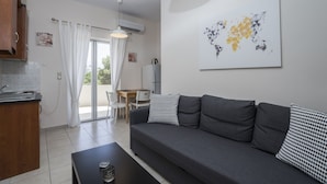 Un salon moderne avec un canapé gris, des coussins aux motifs noir et blanc, une table basse et une œuvre d’art représentant une carte du monde accrochée au mur.