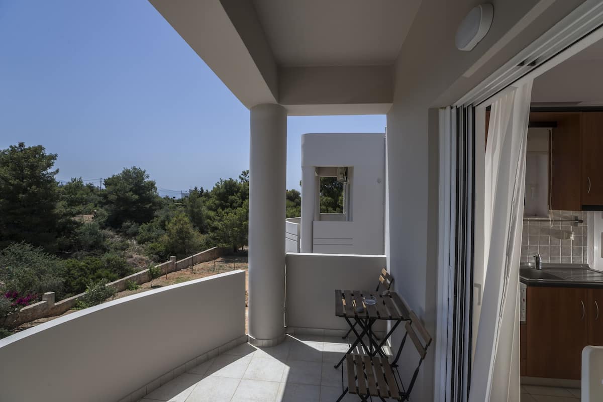 Un balcon avec une table et des chaises, une vue sur le paysage environnant et un aperçu de la cuisine.