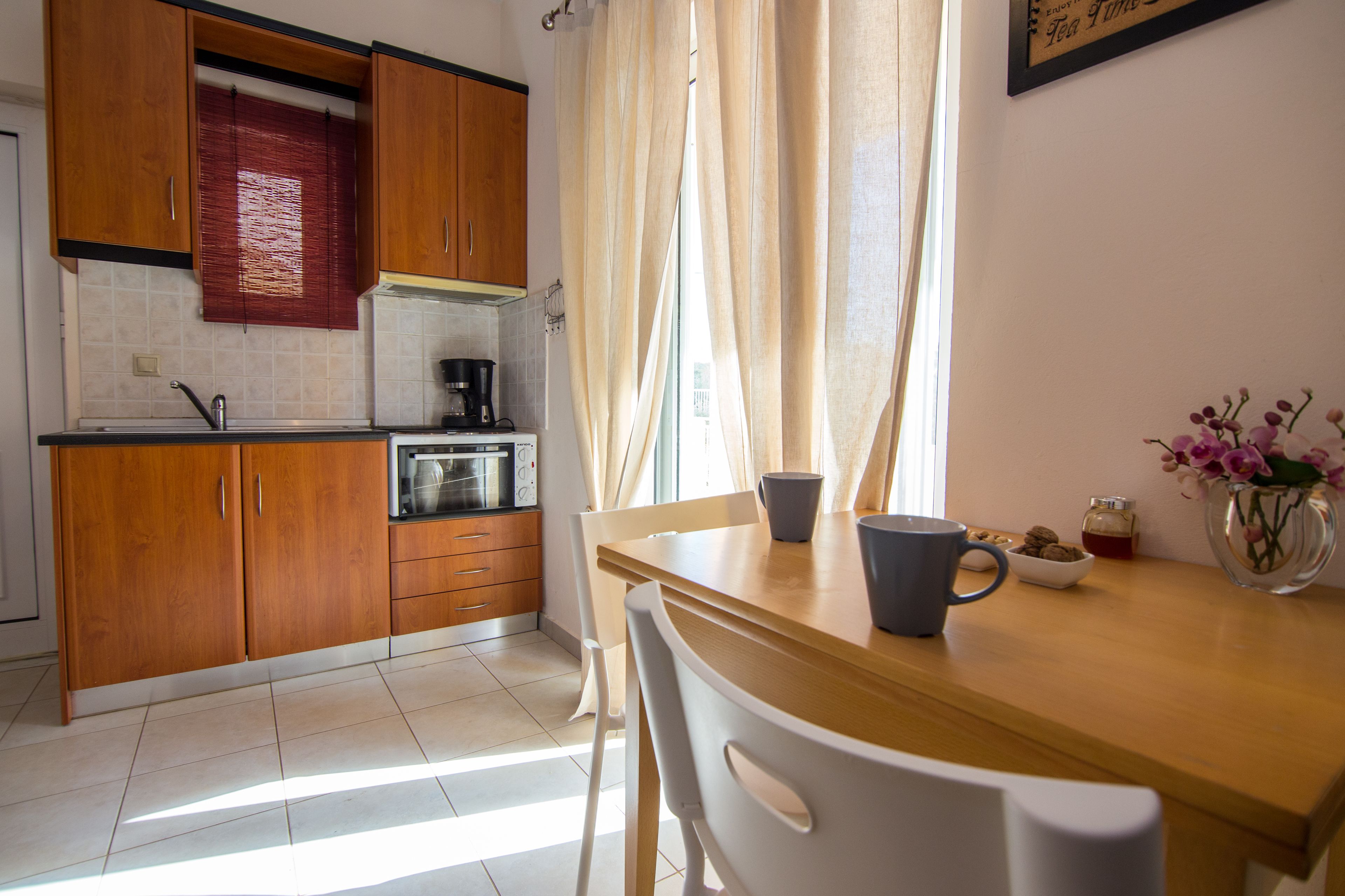 A kitchen with wooden cabinets, a coffee maker, and a dining table with chairs.