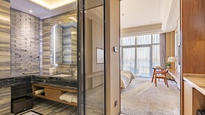 A modern bathroom with a large mirror, a black marble countertop, and a wooden vanity. - Jinling Grand Hotel Nanchang (Nanchang)