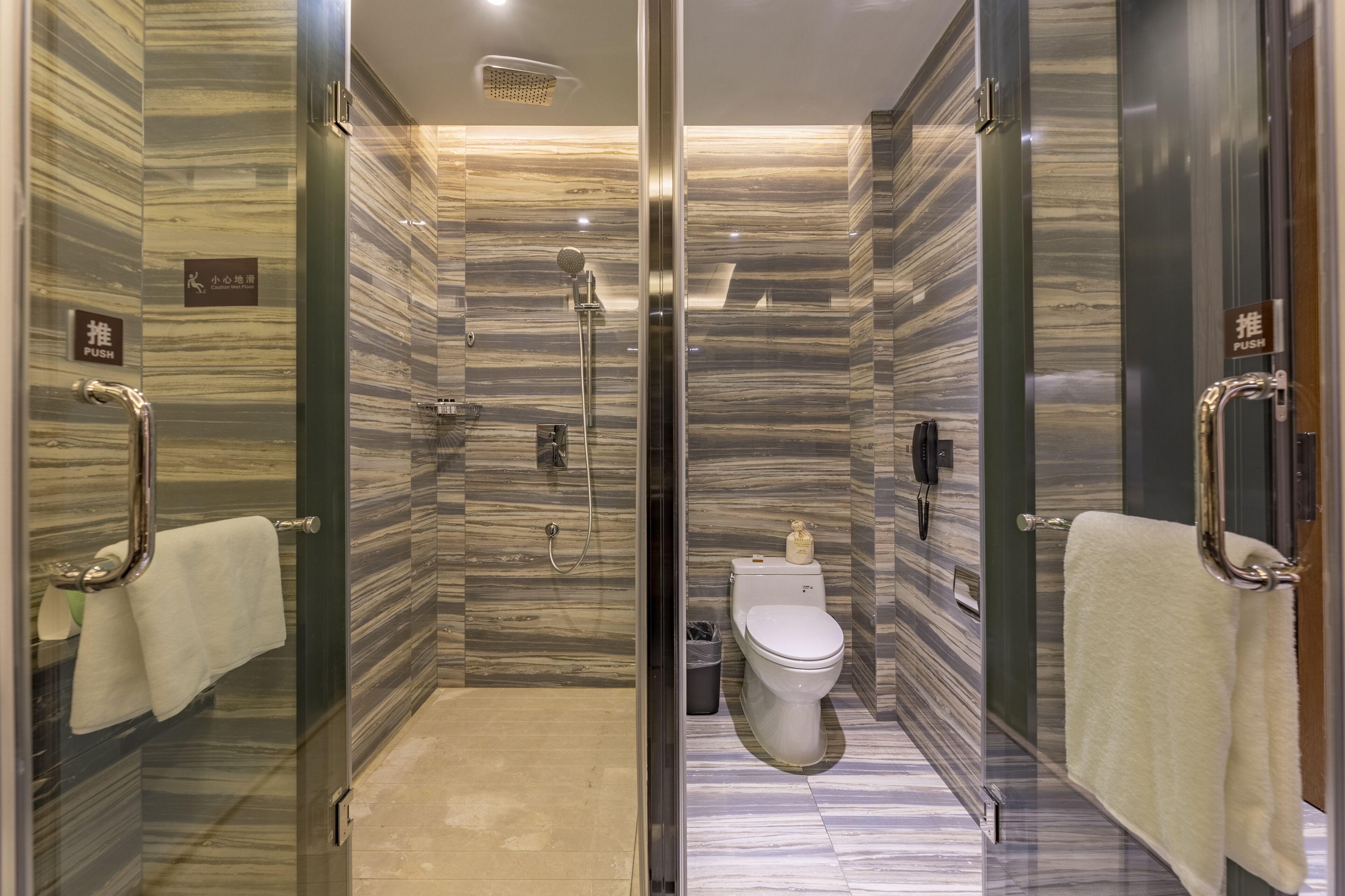 A modern bathroom with a glass-enclosed shower, a toilet, and a bidet.