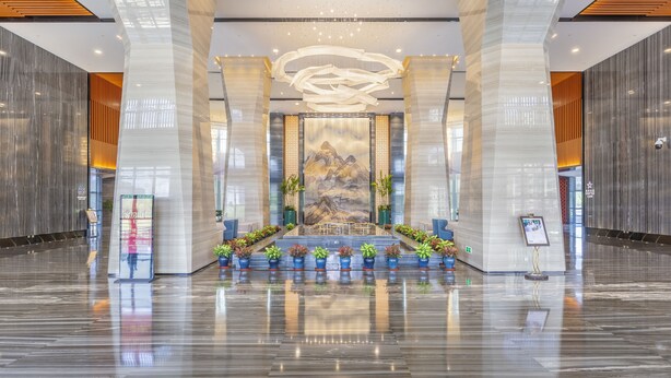 A spacious lobby with a central art installation, a reception desk, and potted plants. - Jinling Grand Hotel Nanchang (Nanchang)