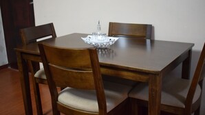 Een eettafel met vier houten stoelen, een decoratieve schaal in het midden, en een deur op de achtergrond.