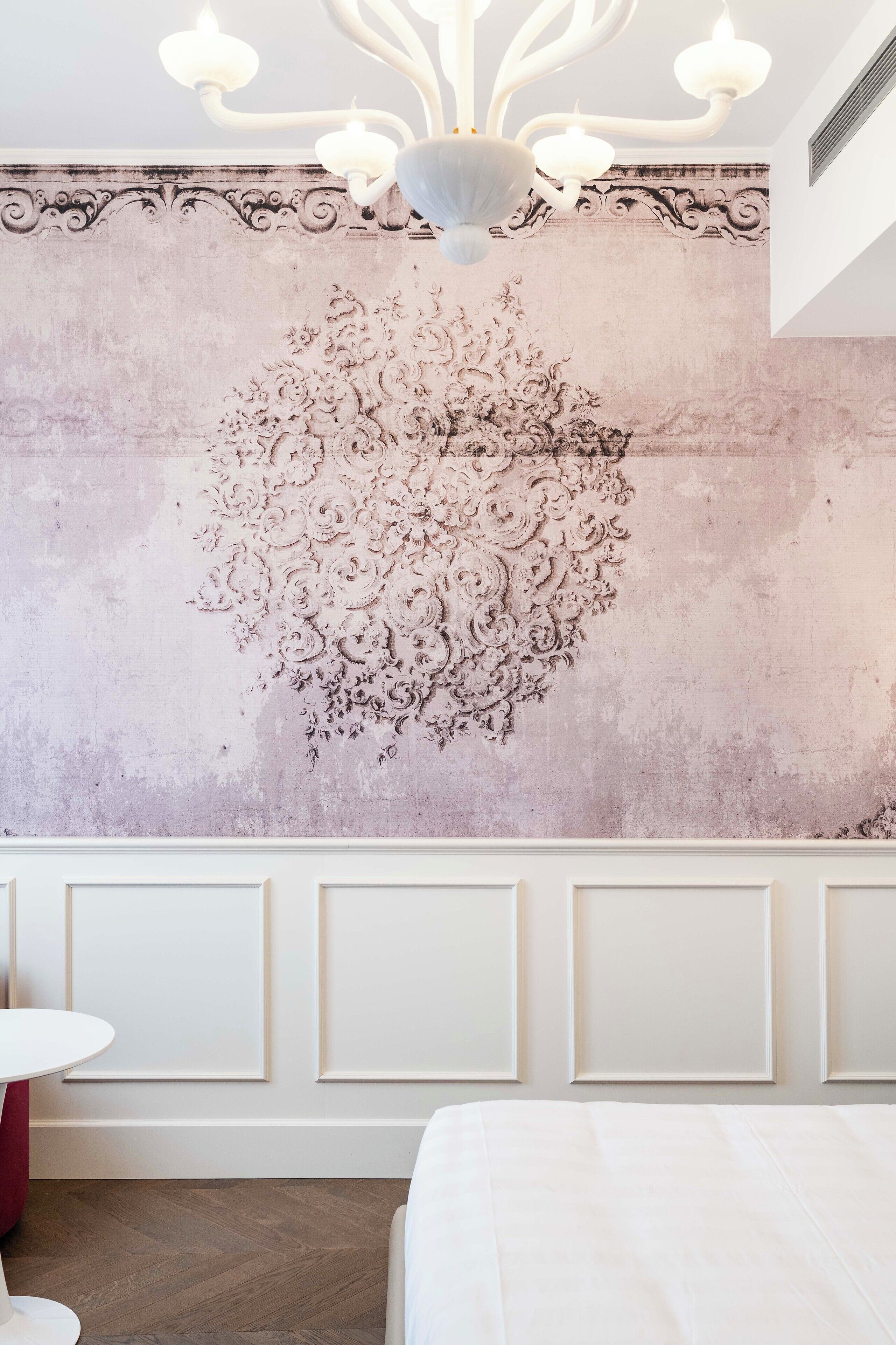 Una habitación con un muro decorativo, una araña y una cama.