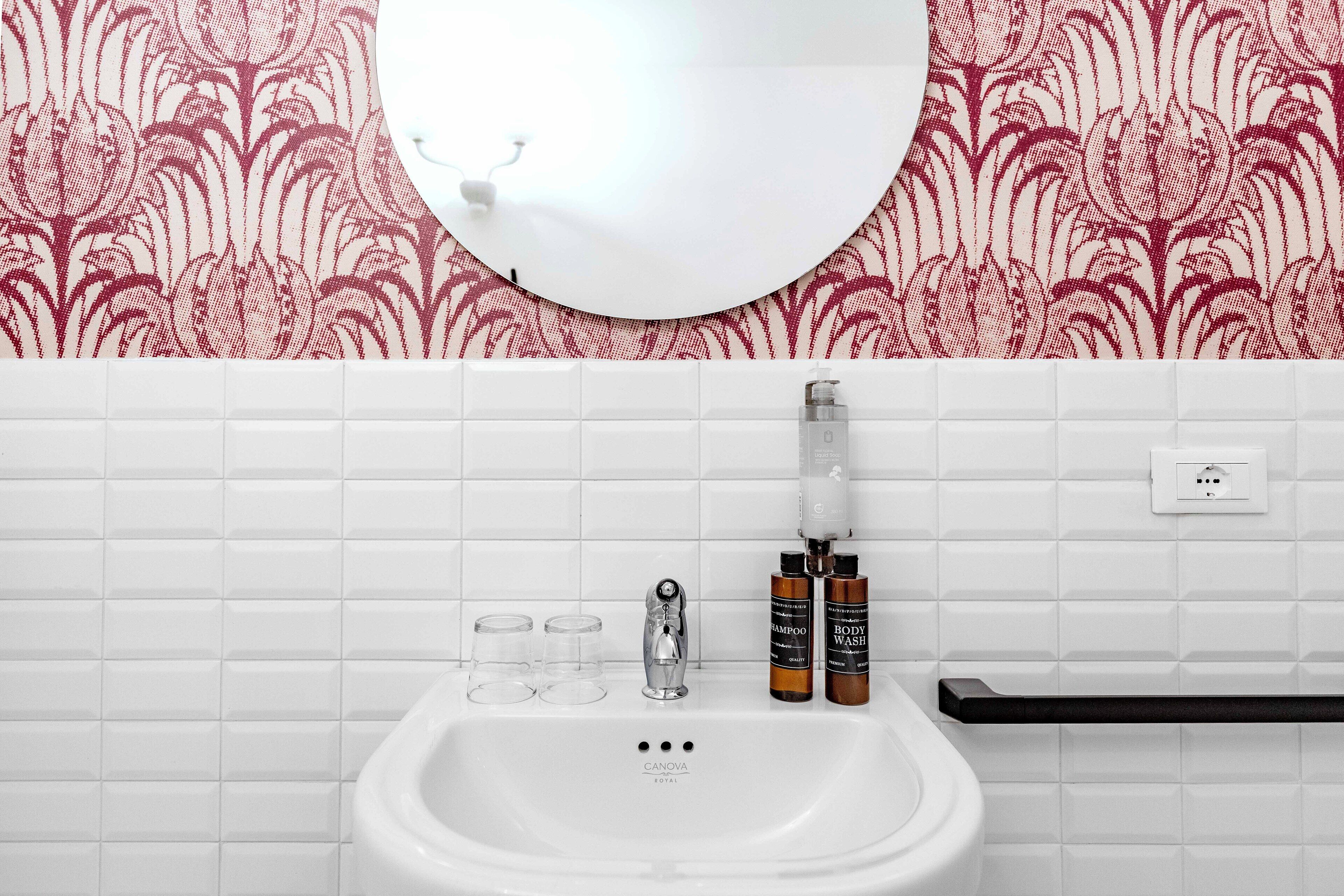 Kylpyhuoneessa on valkoinen pesuallas, peili sekä kaksi pulloa shampoota ja suihkugeeliä.