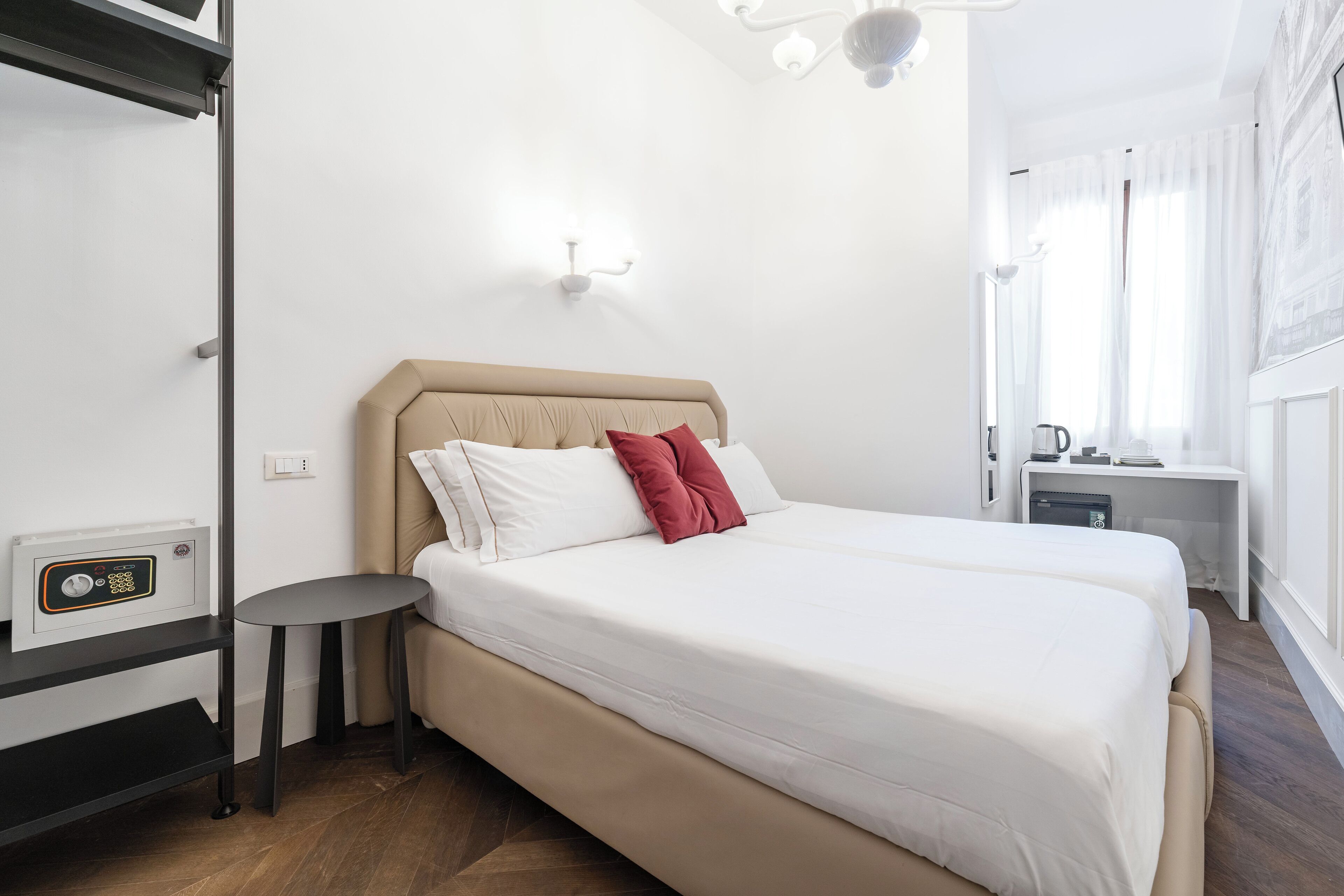 Ein Hotelzimmer mit Bett, Nachttisch und kleinem Schreibtisch mit Wasserkocher.