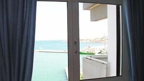 Quarto com vista para o mar através de uma porta de correr.