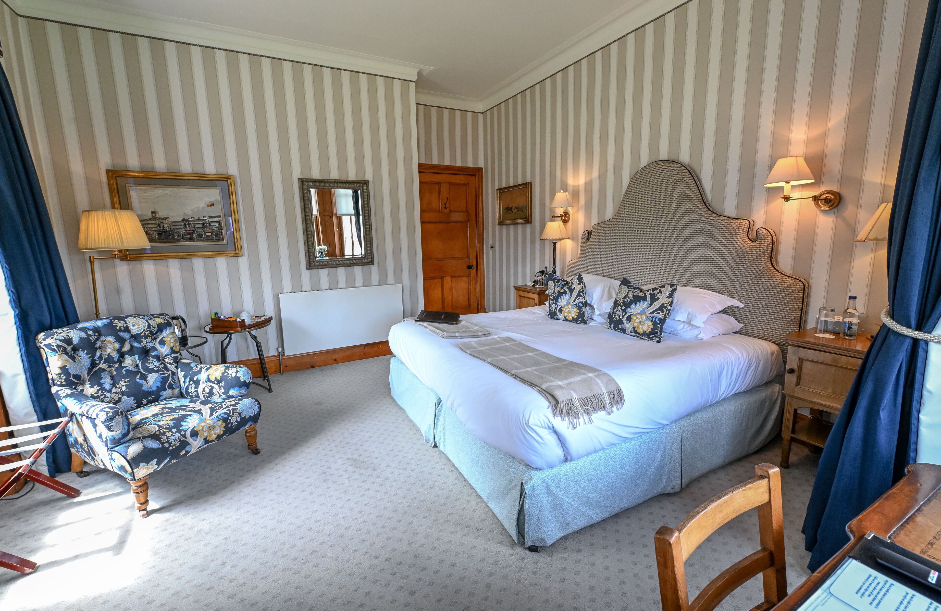 Una habitación de hotel con una cama grande, una silla, un escritorio y una lámpara.