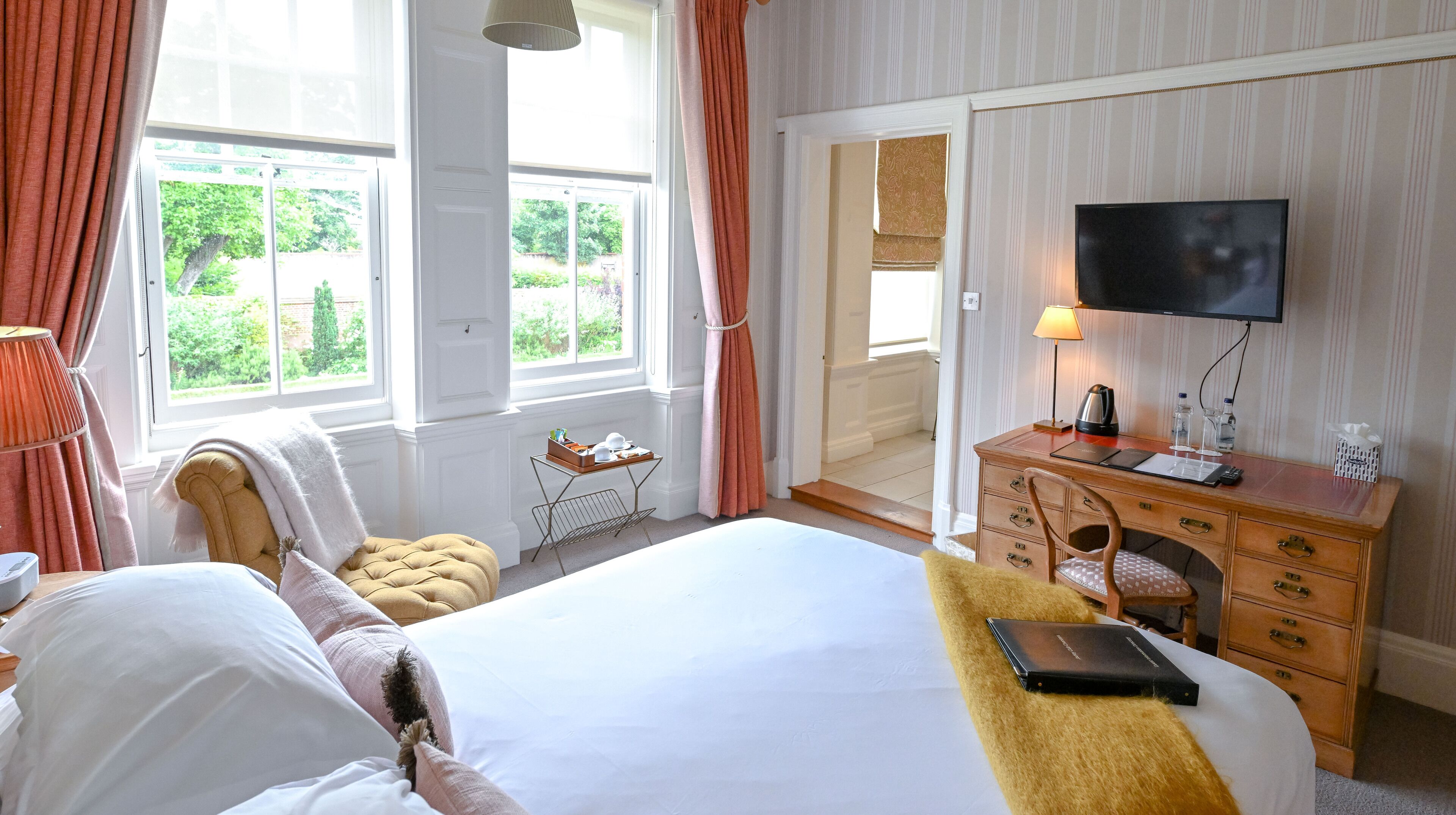 Een hotelkamer met een groot bed, een houten dressoir, een televisie en een raam met gordijnen.