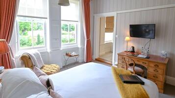 Een hotelkamer met een groot bed, een houten dressoir, een televisie en een raam met gordijnen.