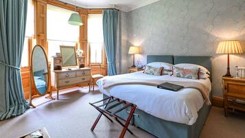 A bedroom with a bed, dresser, mirror, and two bedside lamps.