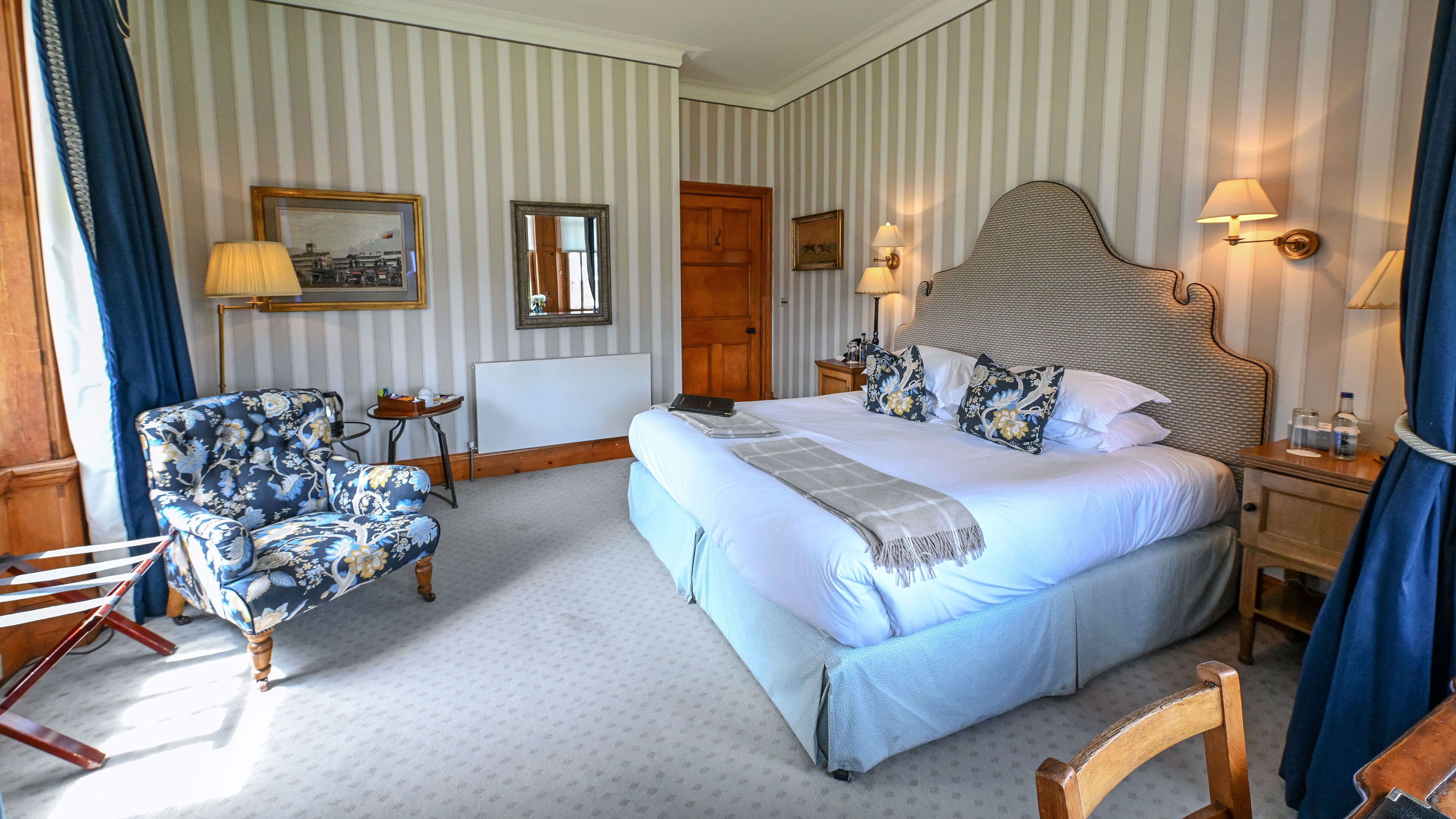 Ein Hotelzimmer mit einem großen Bett, einem Sessel, einem Schreibtisch und einem Spiegel.