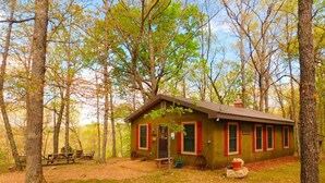 A rustic cabin with a front porch, surrounded by trees. - Rock Eddy Bluff Farm (Dixon)
