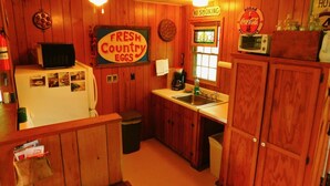 A kitchen with wooden walls, a refrigerator, a coffee maker, and a sign that says "FRESH COUNTRY EGGS". - Rock Eddy Bluff Farm (Dixon)