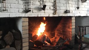 A fireplace with a fire, a white brick wall, and various hanging decorations. - Verde Verde (Punta del Este)
