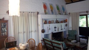 A cozy living room with a fireplace, wooden furniture, and a television. - Verde Verde (Punta del Este)