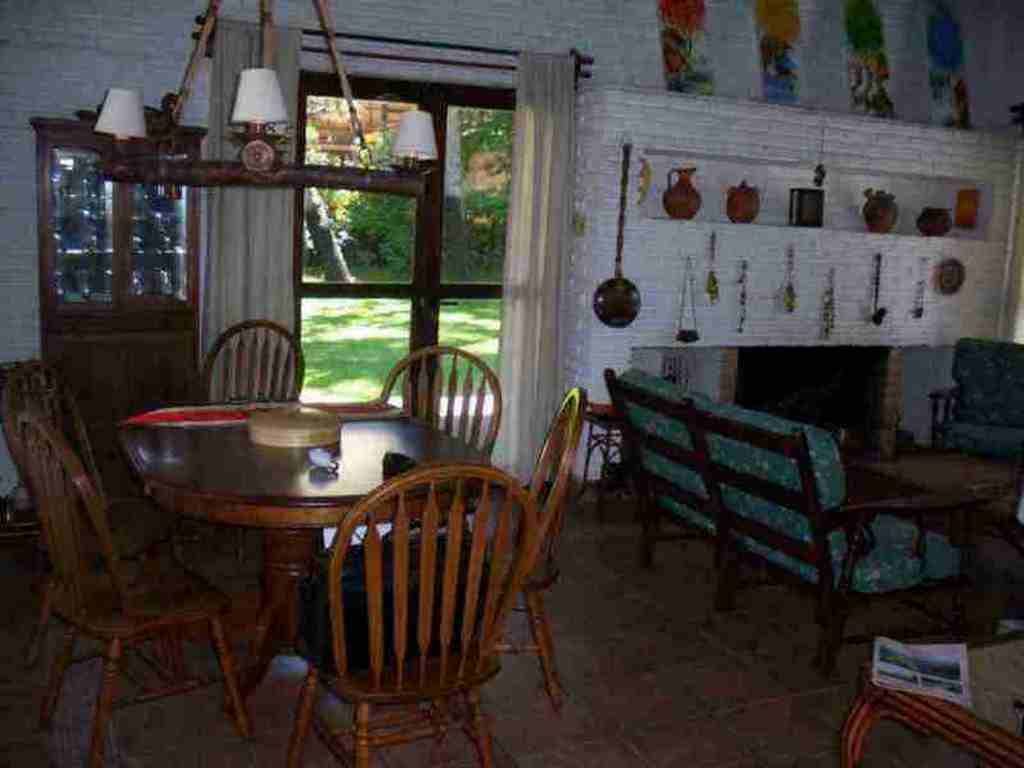 A dining room with a wooden table, chairs, and a fireplace.
