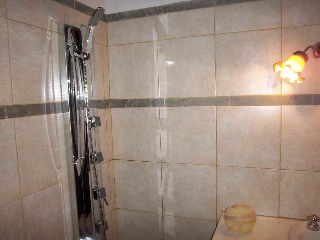 A bathroom with a shower, tiled walls, and a wall-mounted light fixture.
