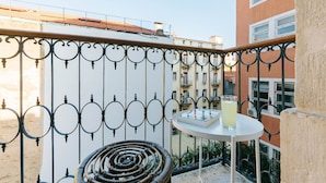 A balcony with a round table, a chair, and a glass of drink. - The Rossio Studio (Lisboa ciudad)