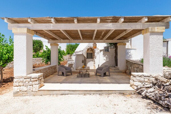 Un espace extérieur am énagé, abrité et doté de murs en pierre et d’une pergola.