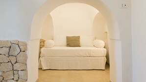 Ein gemütliches Zimmer mit einem Bett unter einer gewölbten Decke, einer Steinsäule und einem Fliesenboden.