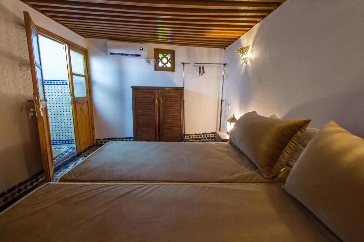 Une chambre dotée d’un grand lit, d’une armoire et d’une porte donnant sur un espace carrelé.