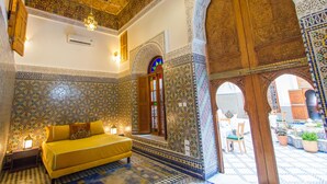 Una habitación con un sofá amarillo, paredes estampadas y una puerta de madera.