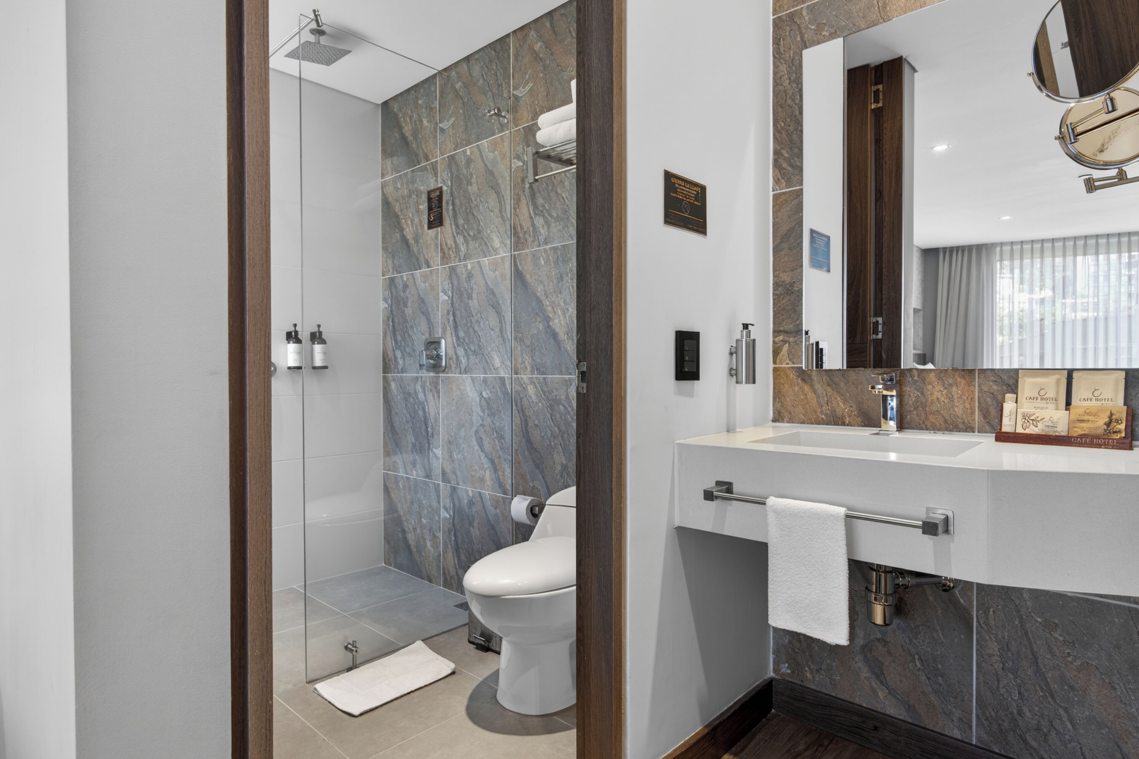 A modern bathroom with a shower, toilet, vanity, and a mirror.