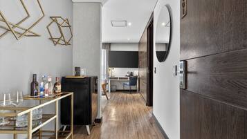 A modern kitchen with a wooden floor, a black refrigerator, and a dining area with a glass table and chairs.