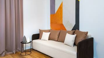 A modern living room with a beige sofa, a small side table, and a geometric wall art piece.