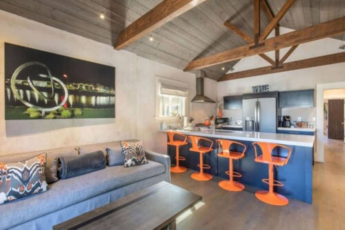 A modern kitchen with a bar area, a sofa, and a large painting on the wall.