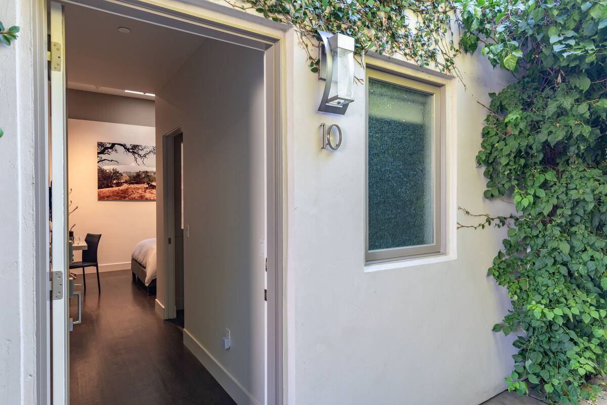A narrow hallway with a bed, a desk, and a chair in a room.