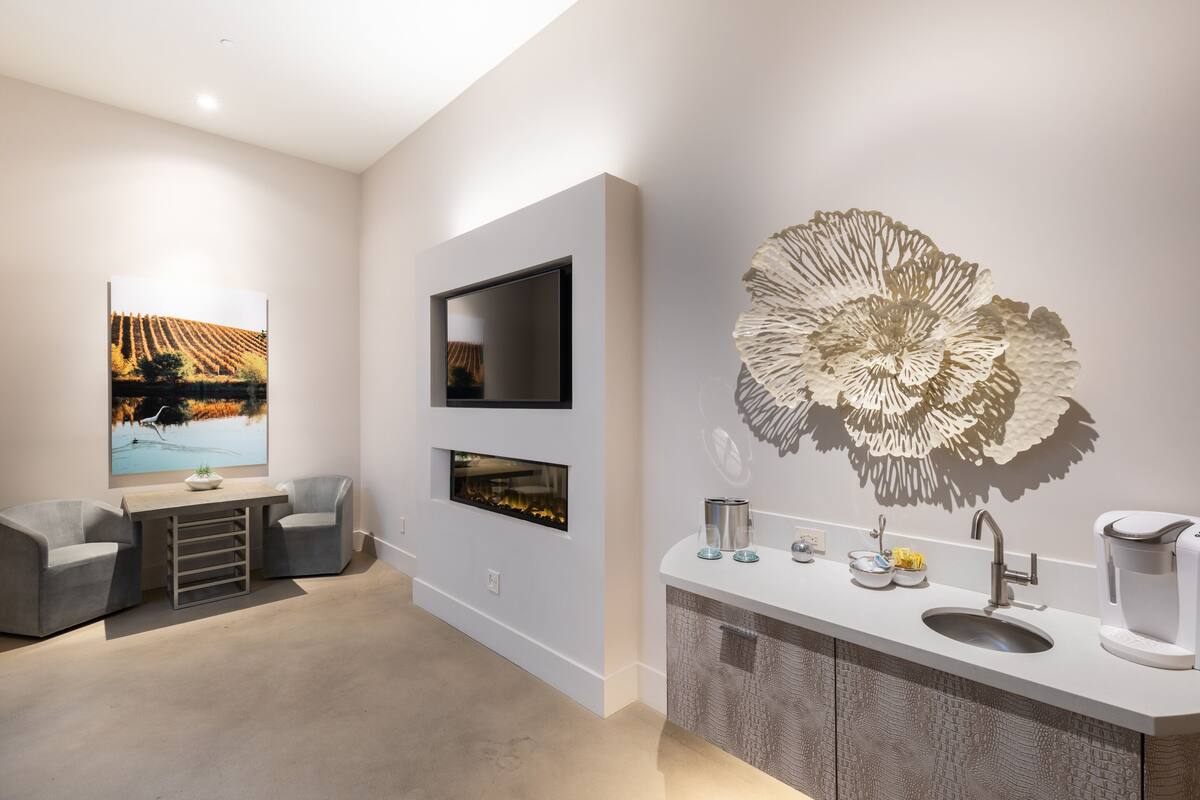 A modern living room with a flat-screen TV, a fireplace, and a large decorative wall piece.