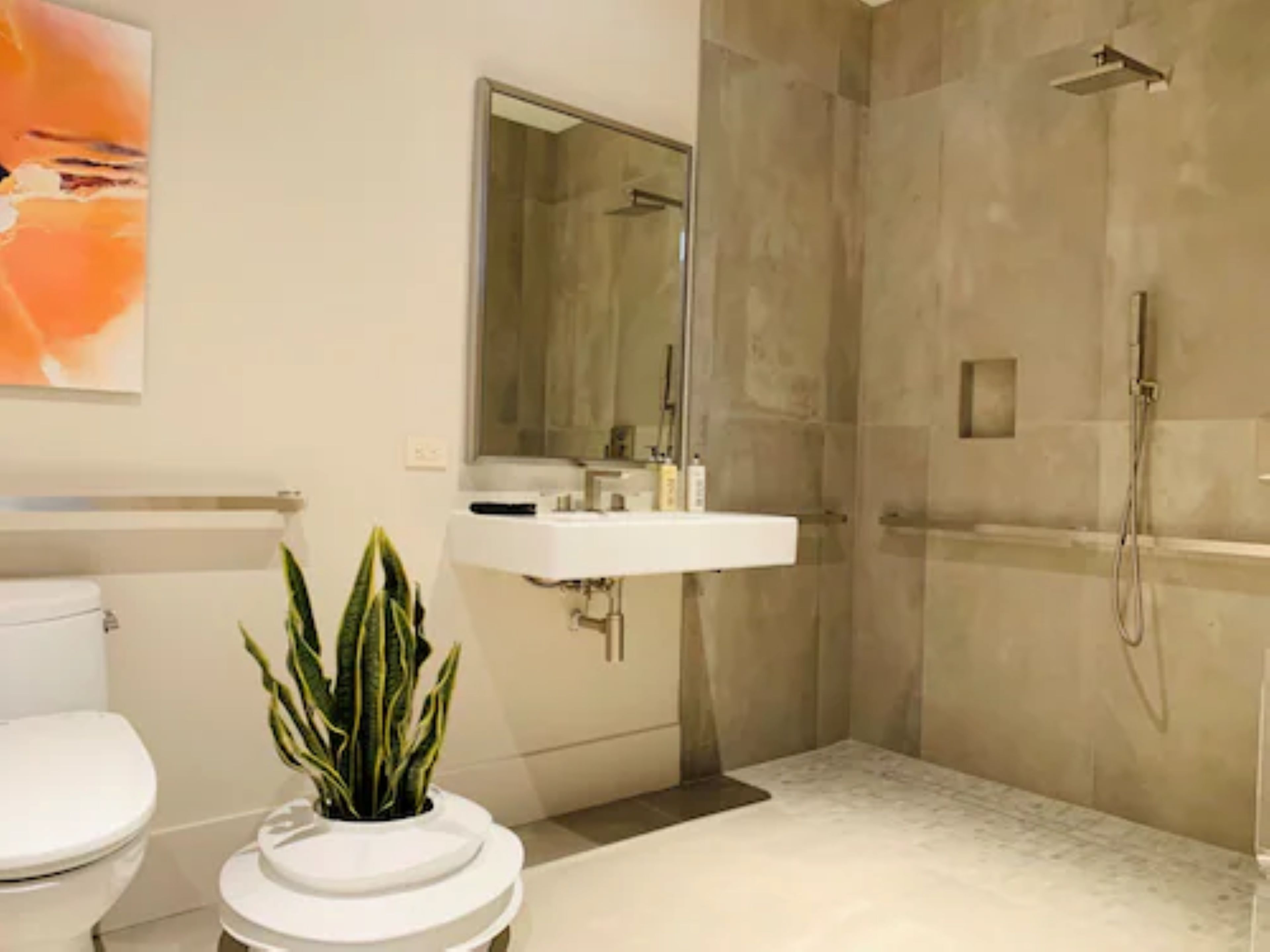 A modern bathroom with a toilet, sink, and shower.