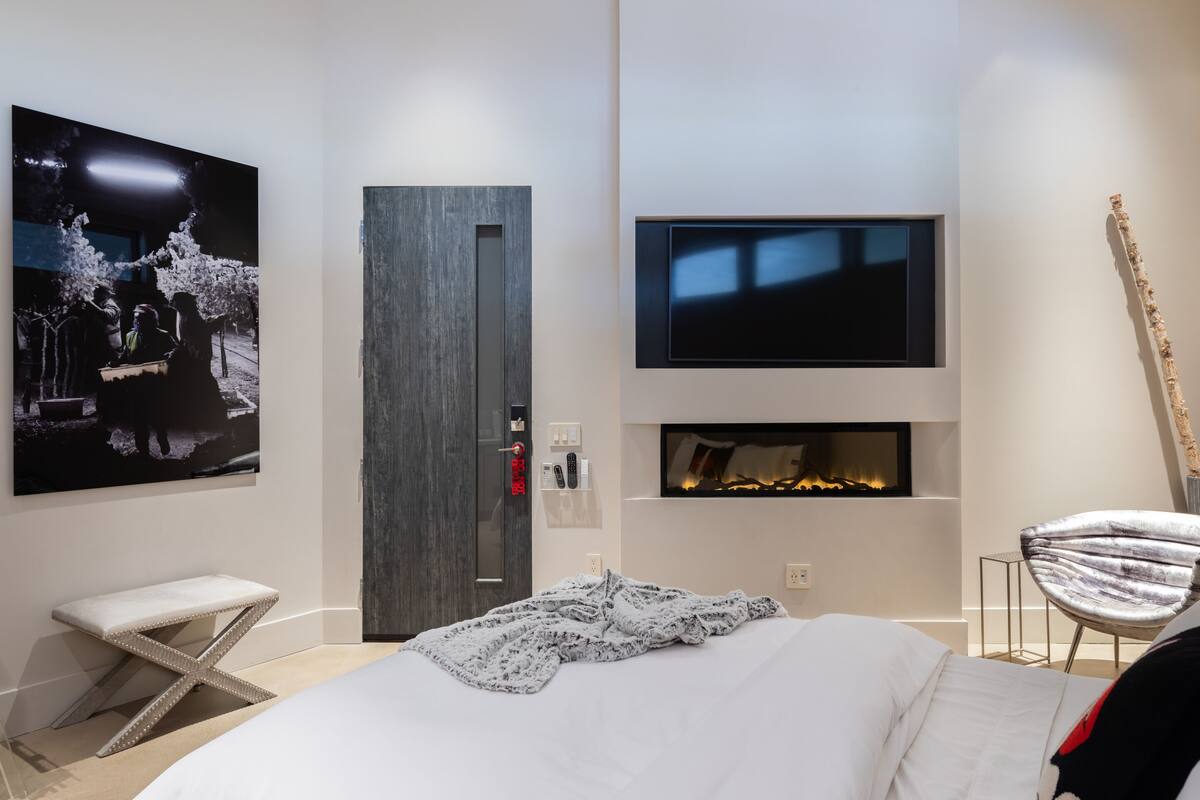 A modern bedroom with a bed, a television, a fireplace, and a unique star-shaped stool.