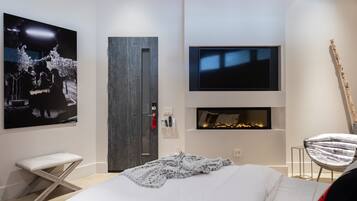 A modern bedroom with a bed, a television, a fireplace, and a unique star-shaped stool.