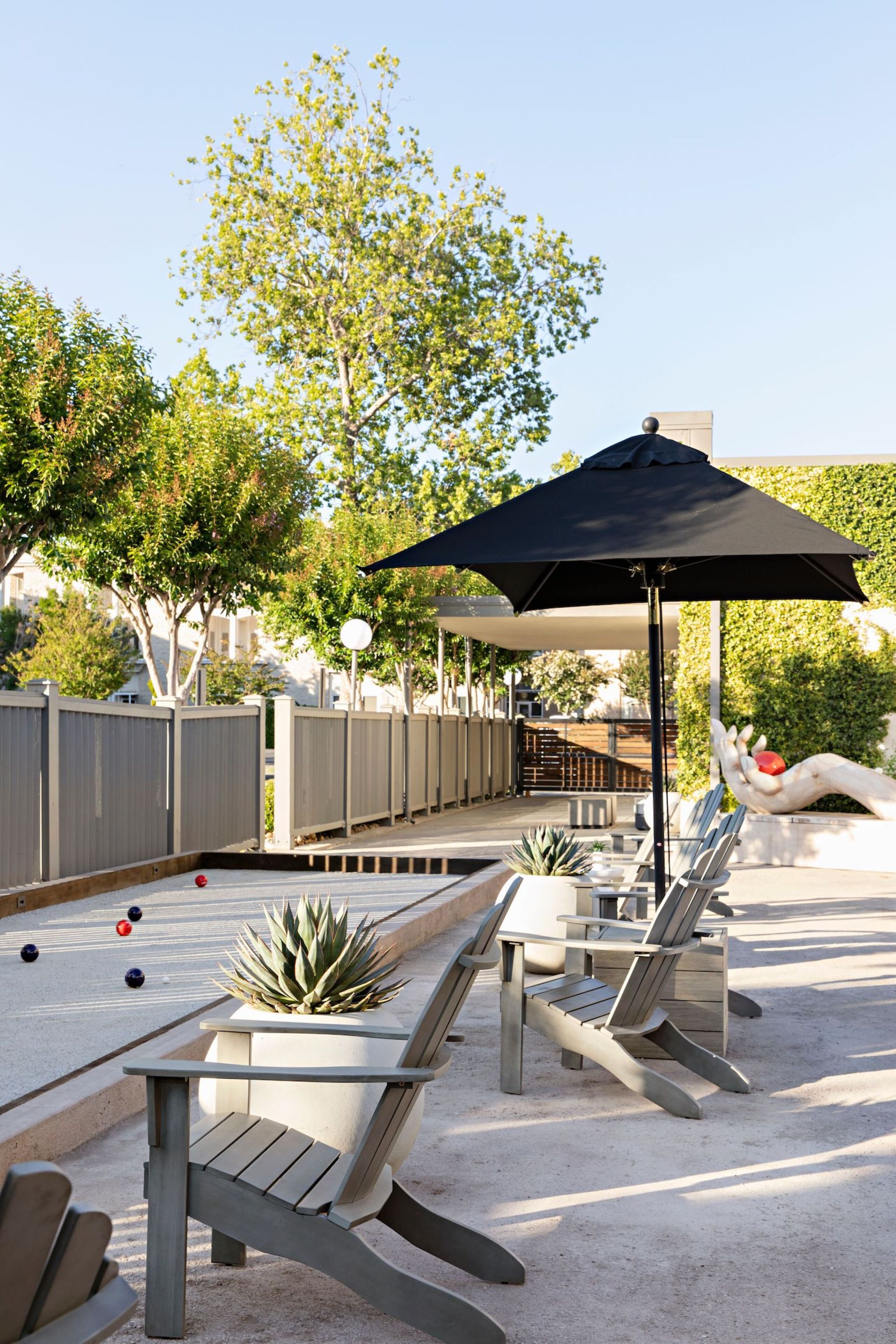 A poolside area with lounge chairs, a table, and a large umbrella.