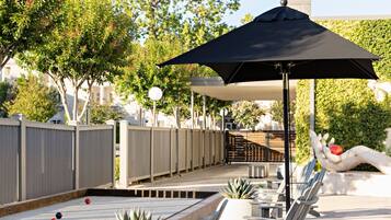 A poolside area with lounge chairs, a table, and a large umbrella.