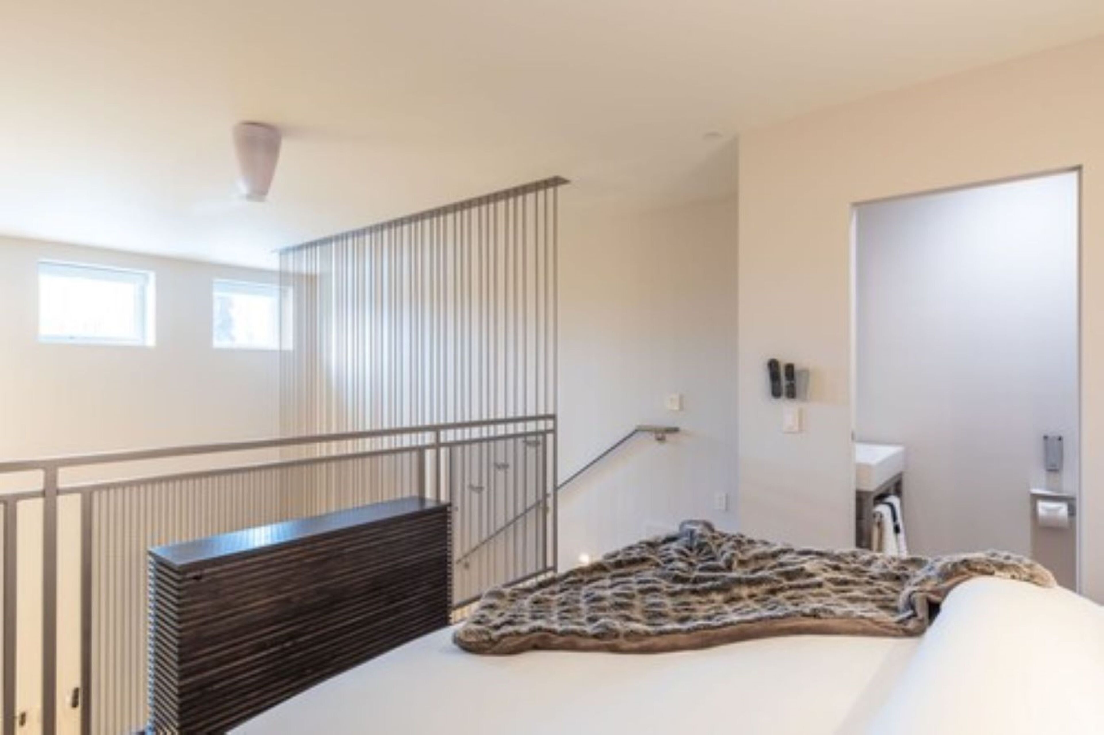 Una habitación de hotel con una cama, un banco, una escalera y una puerta.