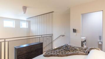 Una habitación de hotel con una cama, un banco, una escalera y una puerta.