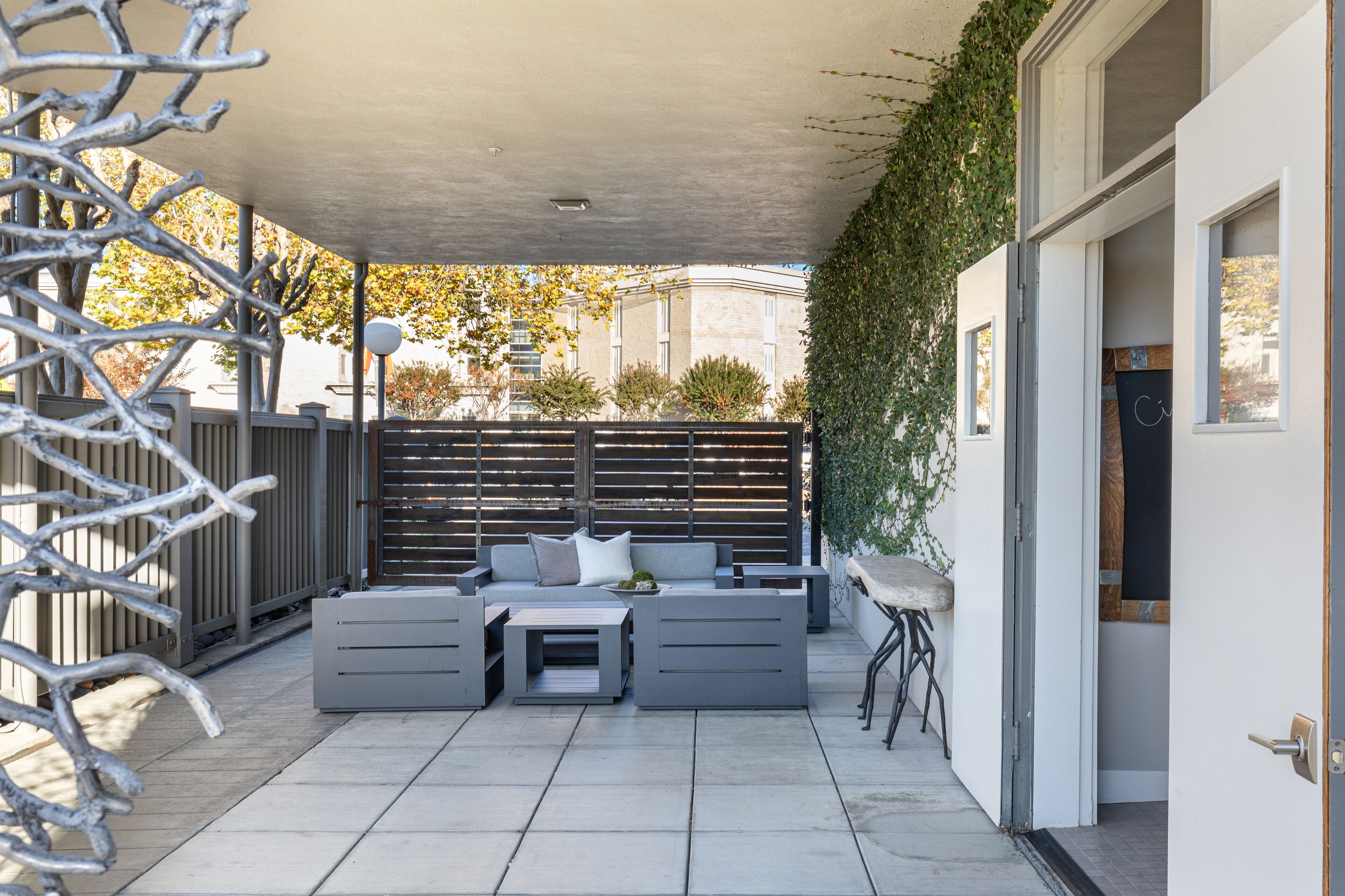 An outdoor patio with a grey sofa set, a small table, and a chair.